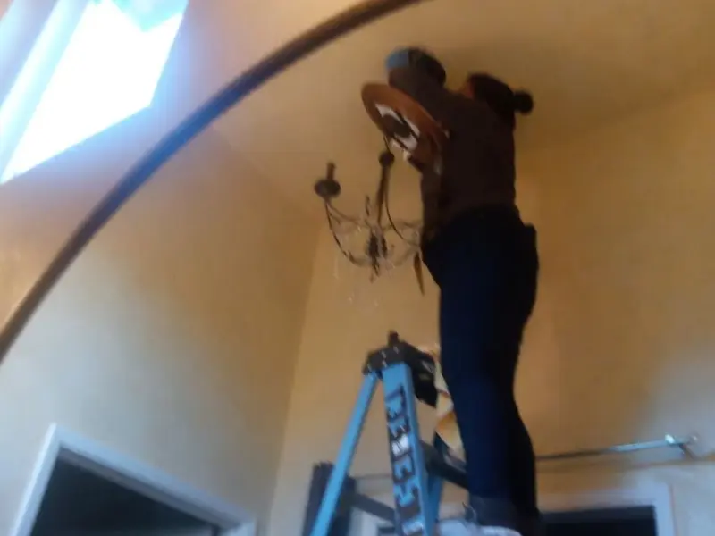Electrician installing a chandelier in a Tucker residence